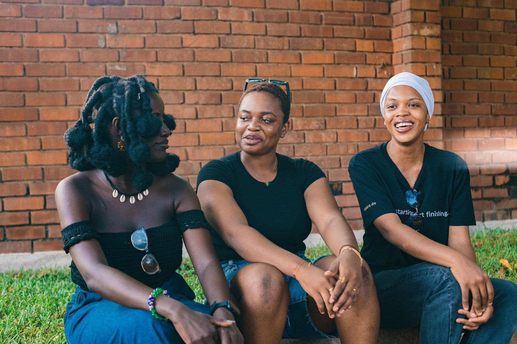 Three friends laughing together outdoors in Accra, Ghana.