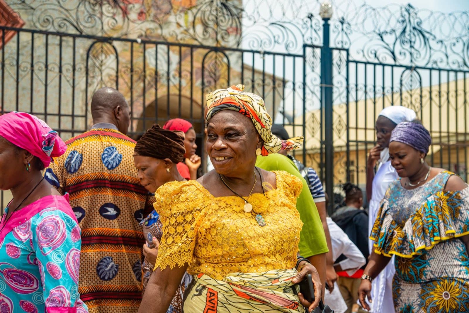 A woman in a golden traditional dress walking through a street in Benin City, Nigeria.